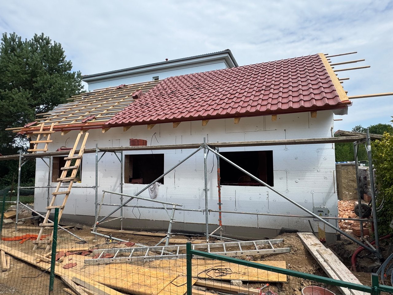 Pokládání střešní krytiny na psí salon Navi, kolem stavby lešení